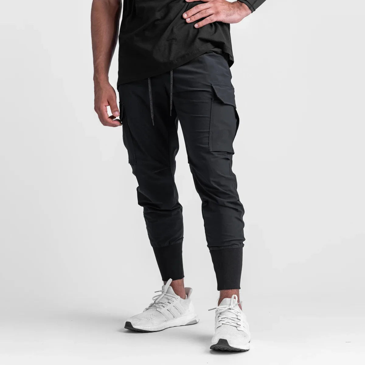 Men's cargo style sports pants in black, featuring a drawstring closure and slim fit for training and performance.