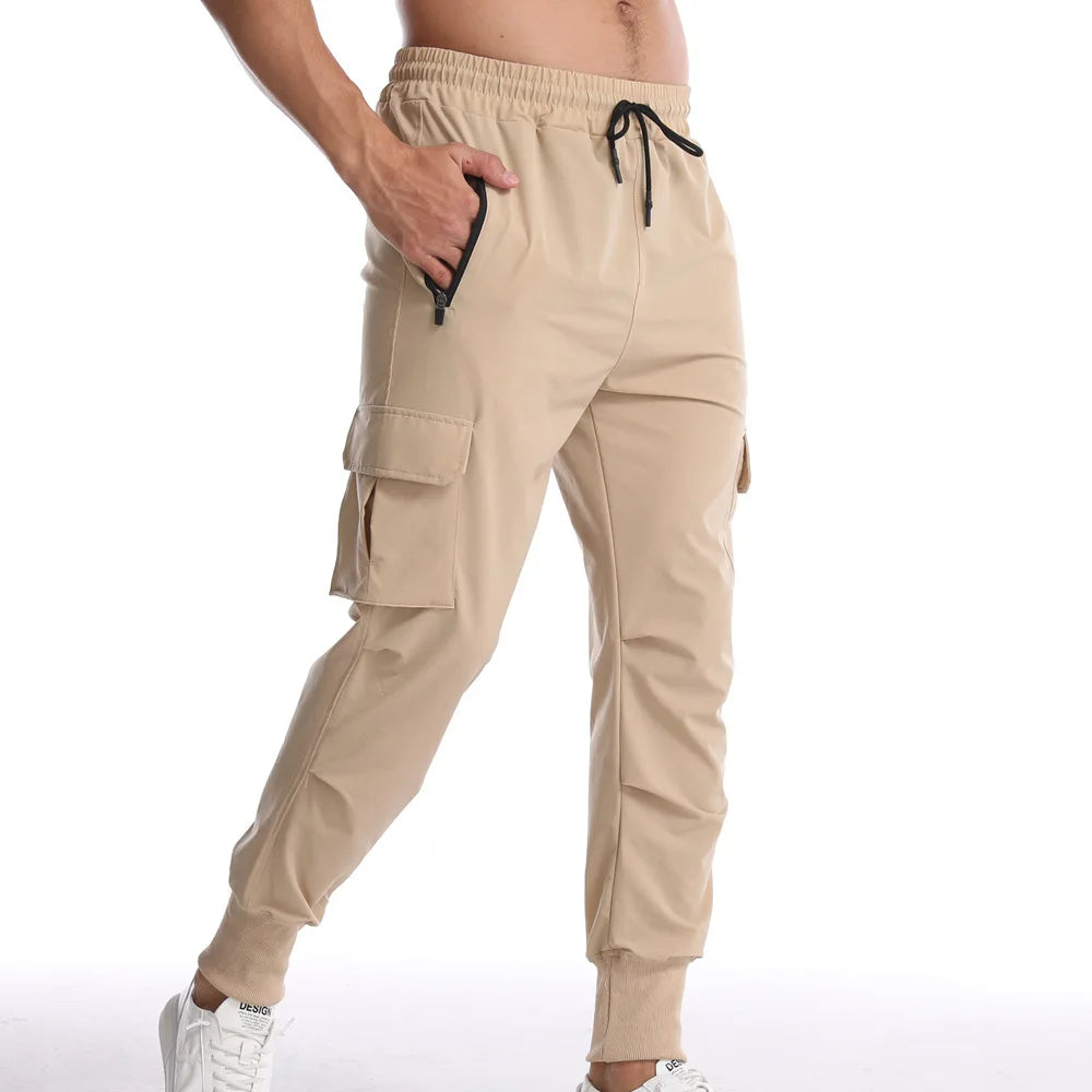 Men's cargo style sports pants in beige, featuring elastic waistband and pockets, perfect for athletic activities.