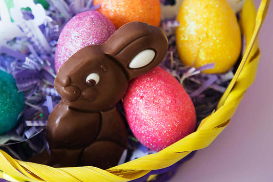 A yellow basket with colored eggs and a bonny chocolate