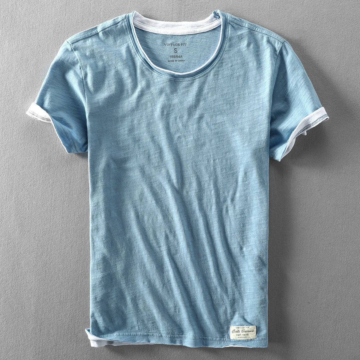 Blue t-shirt with white trim on a gray background