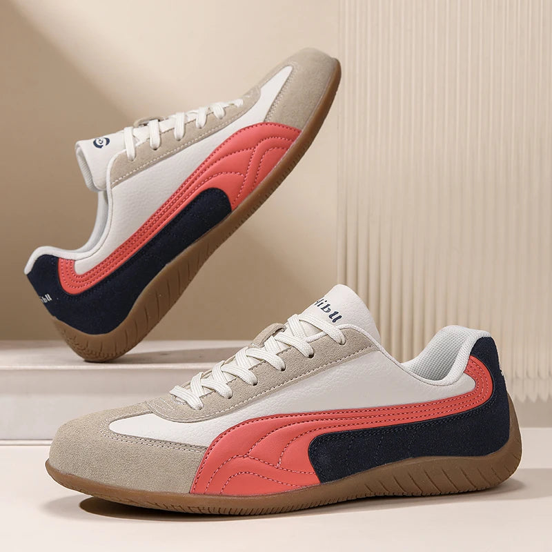 Pair of sneakers with a beige, red, and navy design on a neutral background