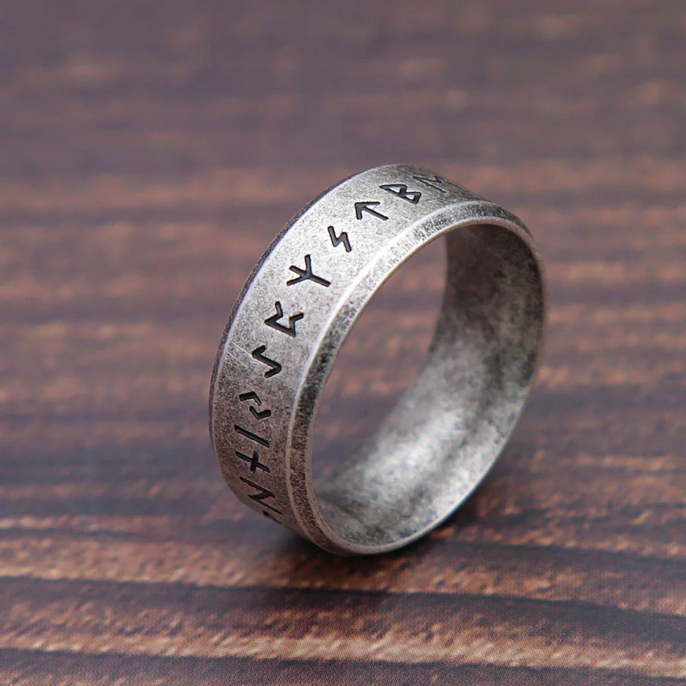 Silver ring with engraved symbols on a wooden surface