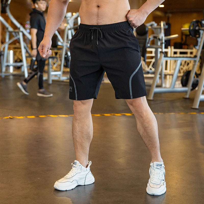 Person wearing black athletic shorts with white sneakers in a gym setting