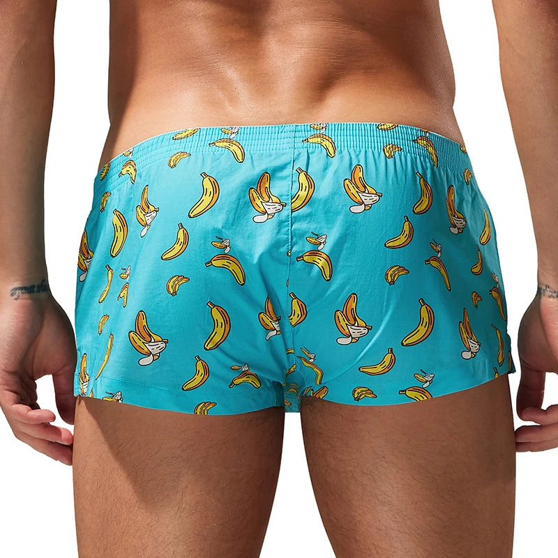 A man's lower torso and thighs are shown from the back wearing turquoise boxer briefs with an all-over yellow banana cartoon print on a white background.