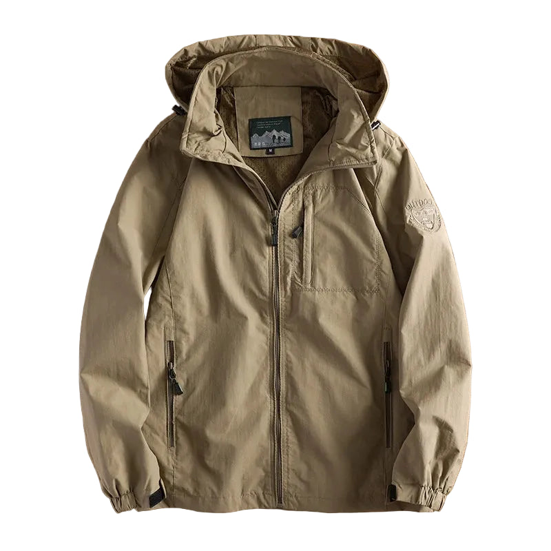 Khaki jacket on a wooden surface with a blurred photo of a living room in the background
