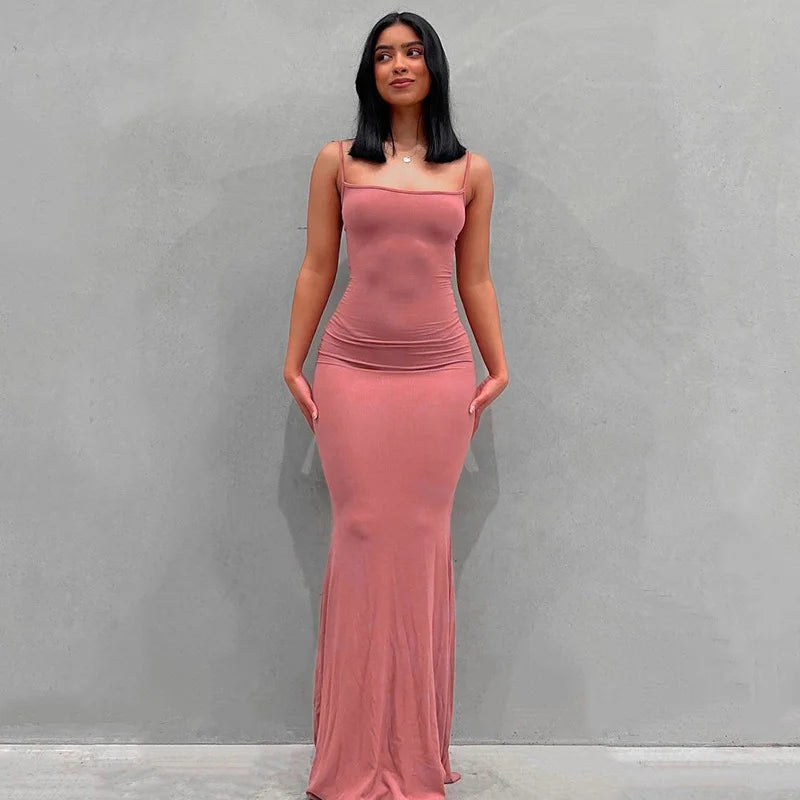 Woman in a sleeveless ankle-length slip dress, showcasing a slim fit and elegant silhouette in a soft pink hue.
