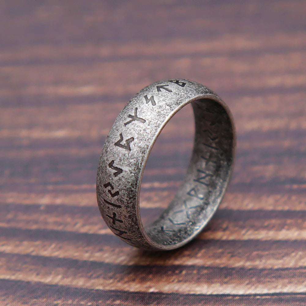 Silver ring with engraved symbols on a wooden surface