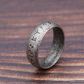 Silver ring with engraved symbols on a wooden surface