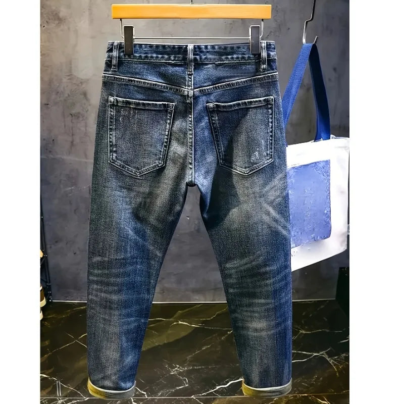 Blue jeans hanging on a rack with a gray wall and marble floor in the background