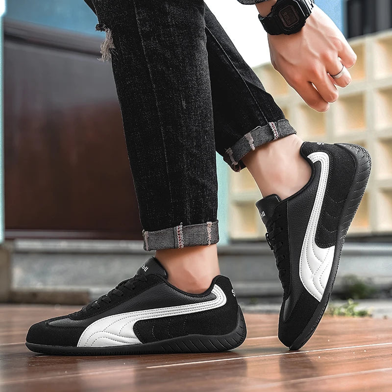 Black and white sneakers worn with rolled-up jeans on a blurred indoor background