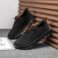 Black sneakers with orange accents on a gray surface with wooden slats in the background