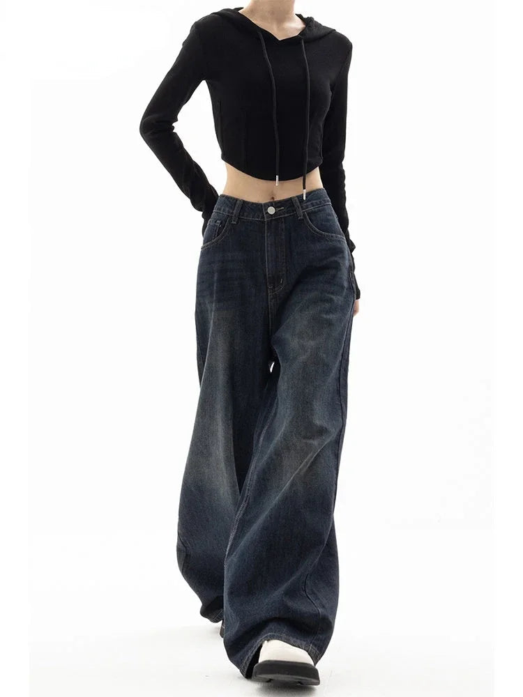 Person wearing a black cropped hoodie and wide-leg jeans on a white background