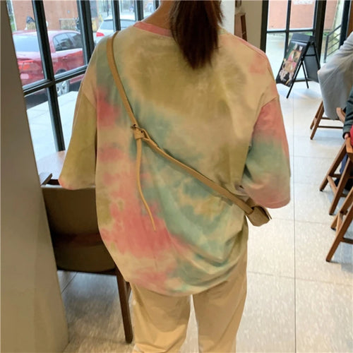 Colorful tie dye t-shirt in pastel shades, worn casually for a relaxed summer look.