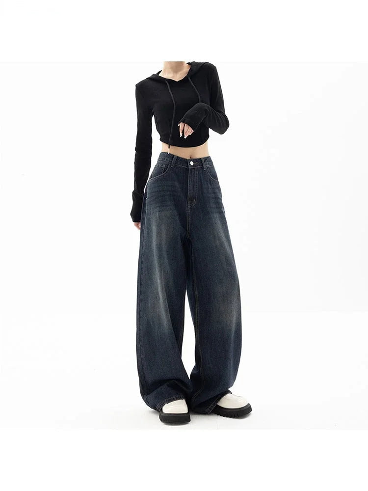 Person wearing a black long-sleeve top and wide-leg jeans on a white background