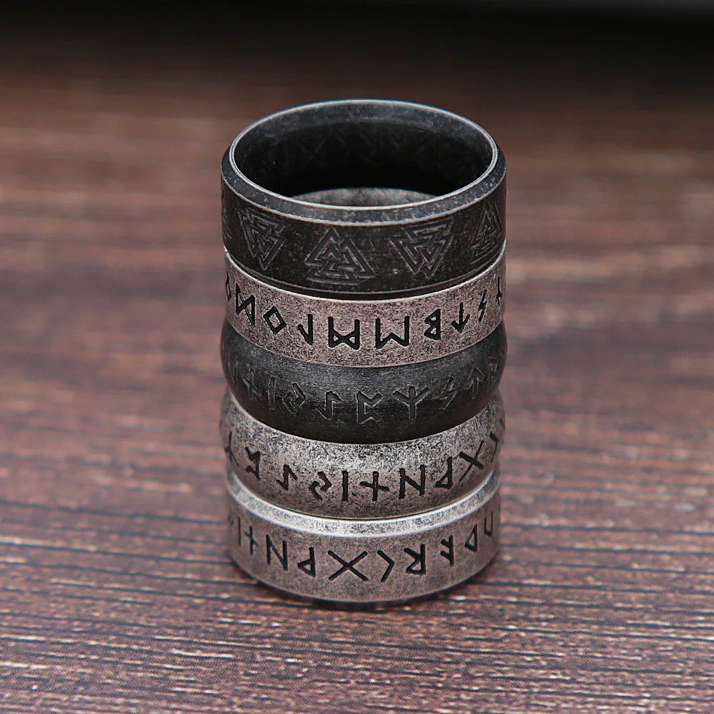 Stack of metallic rings with engraved patterns on a wooden surface