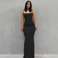 Woman wearing a sleek black ankle-length slip dress with spaghetti straps and a fitted silhouette.