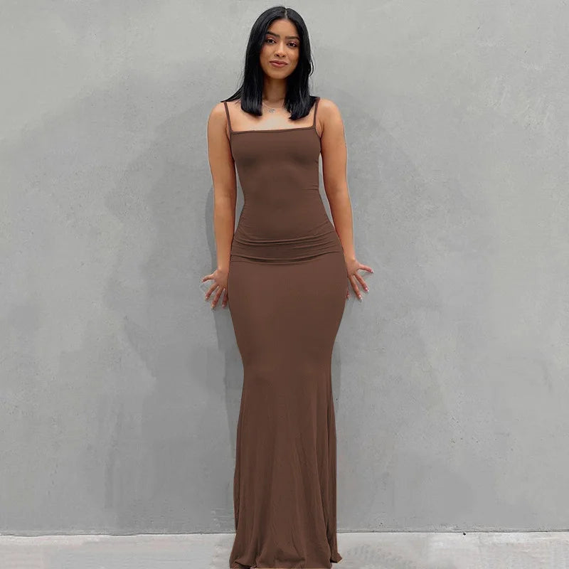 Sleek brown ankle-length slip dress on a model, showcasing a slim fit and spaghetti straps against a neutral background.