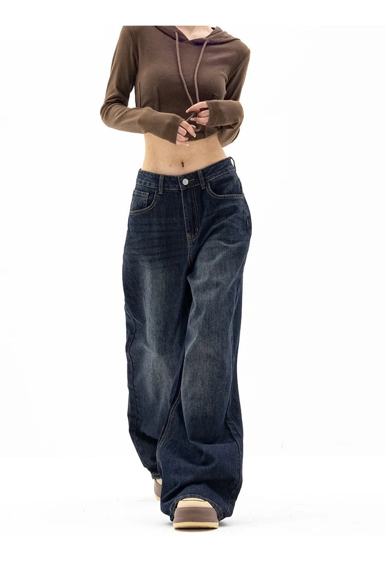 Person wearing a brown cropped hoodie and blue jeans on a white background