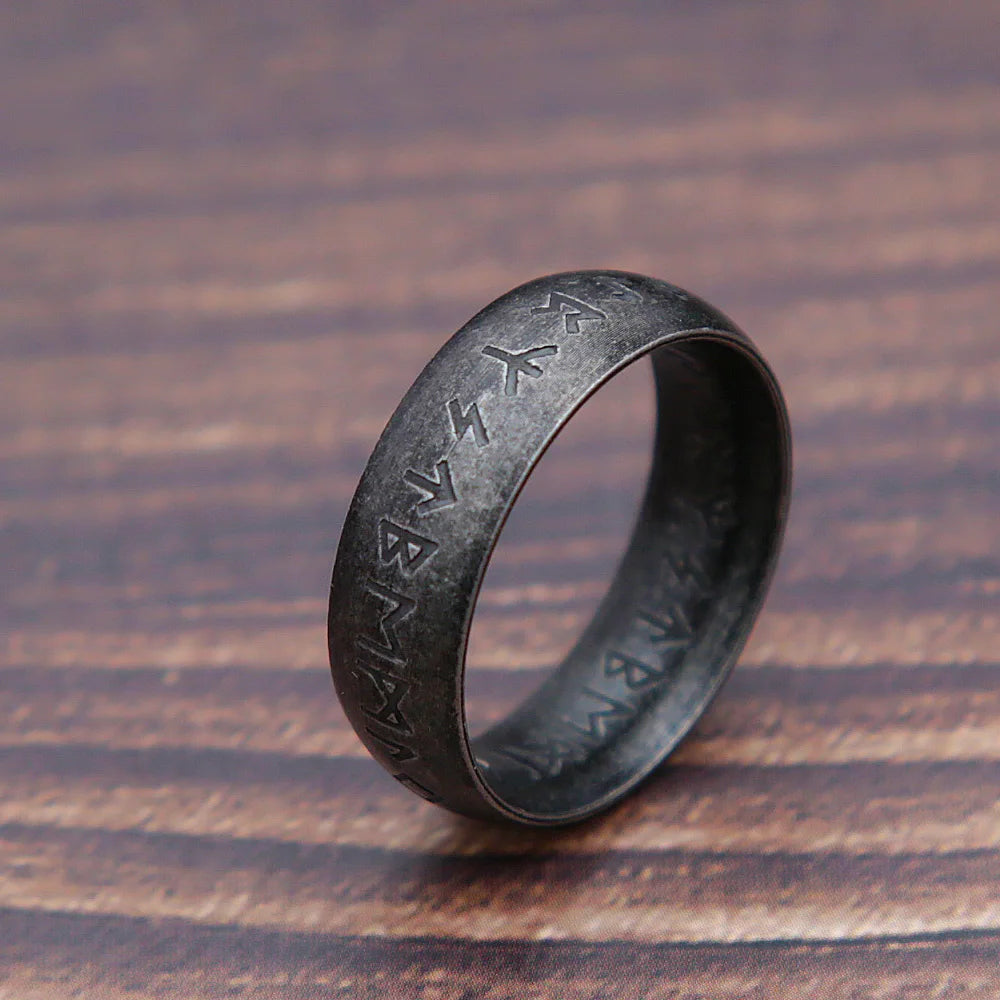 Black ring with engraved symbols on a wooden surface