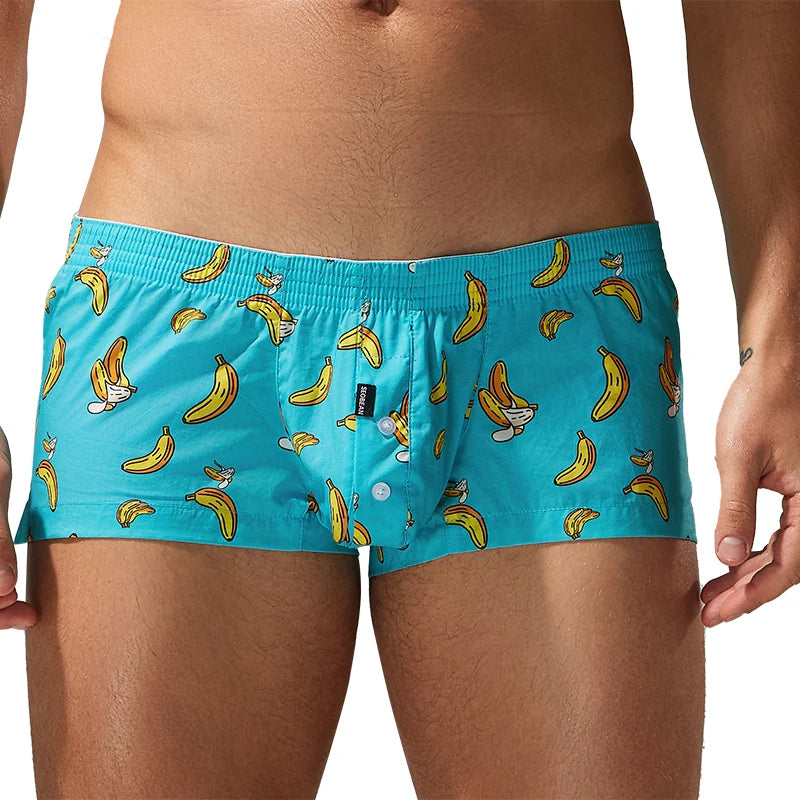 Men's boxer briefs in bright turquoise blue with a repeating cartoon banana and rabbit print, shown on a cropped male model against a white studio background.