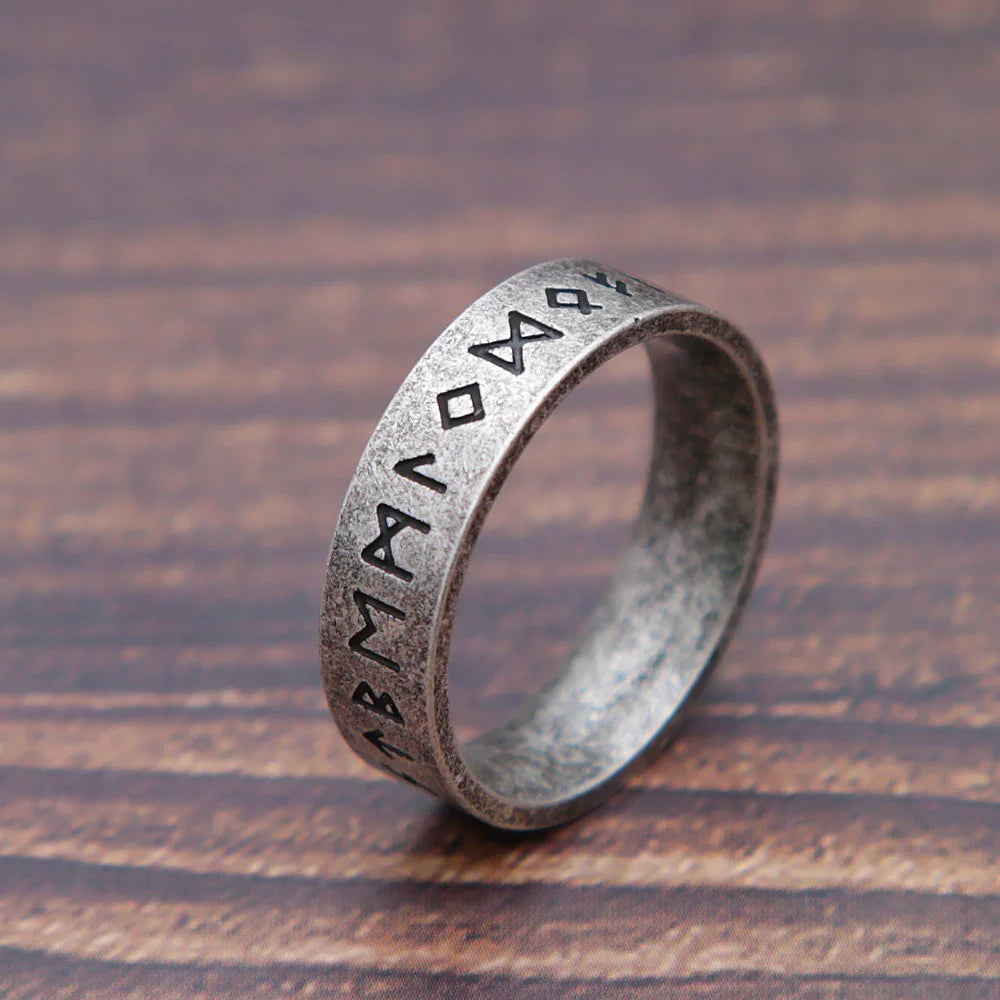 Silver ring with engraved symbols on a wooden surface