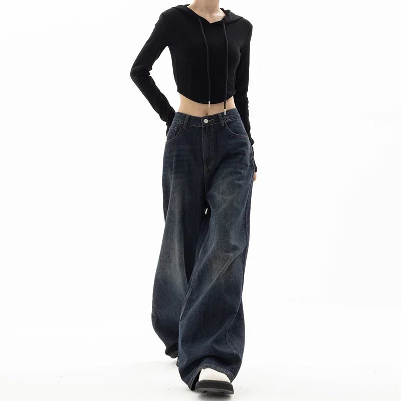 Person wearing a black cropped top and wide-leg jeans on a white background