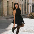 Model wearing The Perfect Halter Dress, showcasing a chic black A-line design on a European street.