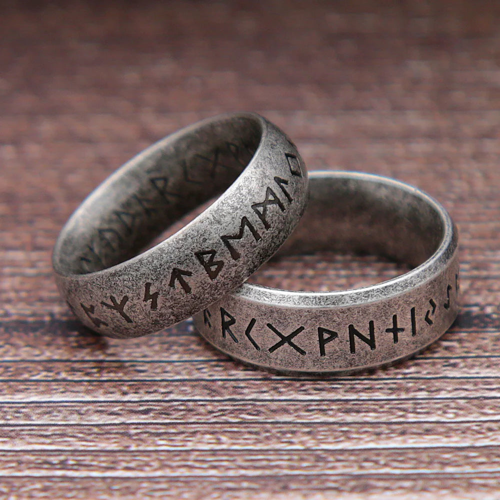 Two silver rings with engraved symbols on a wooden surface