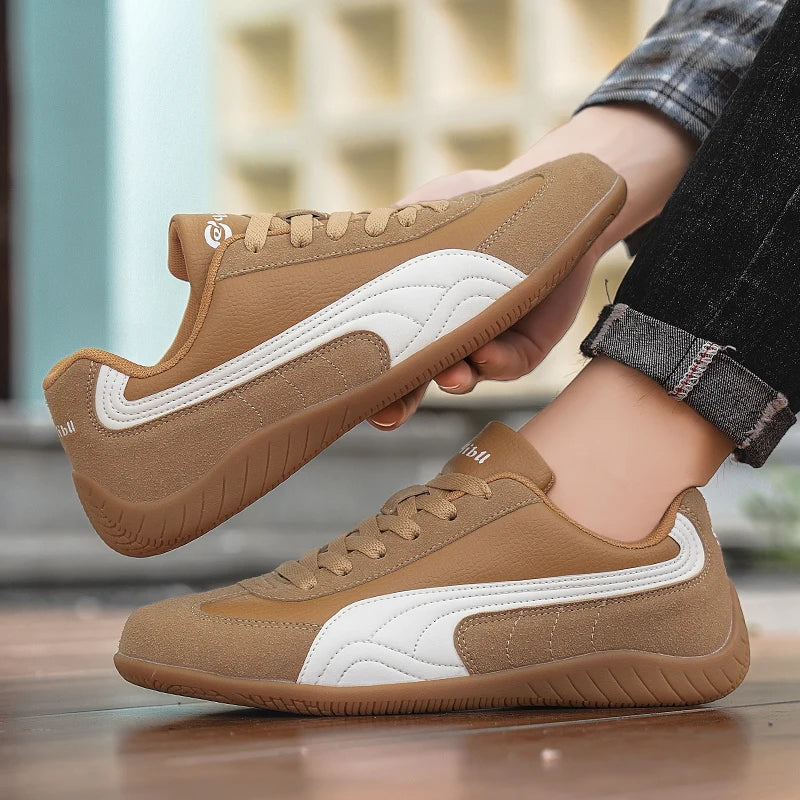 Brown sneakers with white accents held by a person against a blurred indoor background